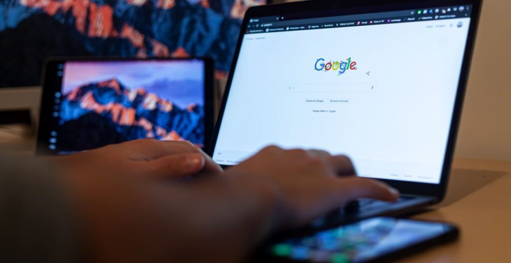 Mãos digitando em um laptop com a busca do Google aberta